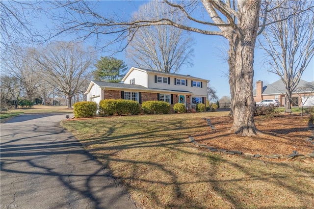 colonial-style house featuring a garage and a front lawn