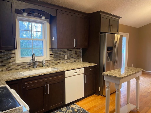 kitchen featuring dishwasher, light stone countertops, sink, and light wood-type flooring