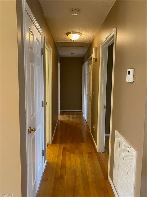 corridor featuring light hardwood / wood-style flooring and a textured ceiling