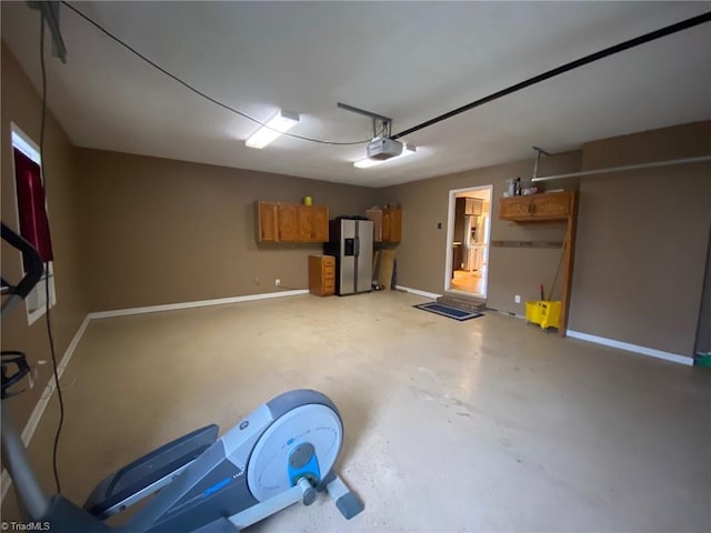 garage with a garage door opener and stainless steel refrigerator with ice dispenser