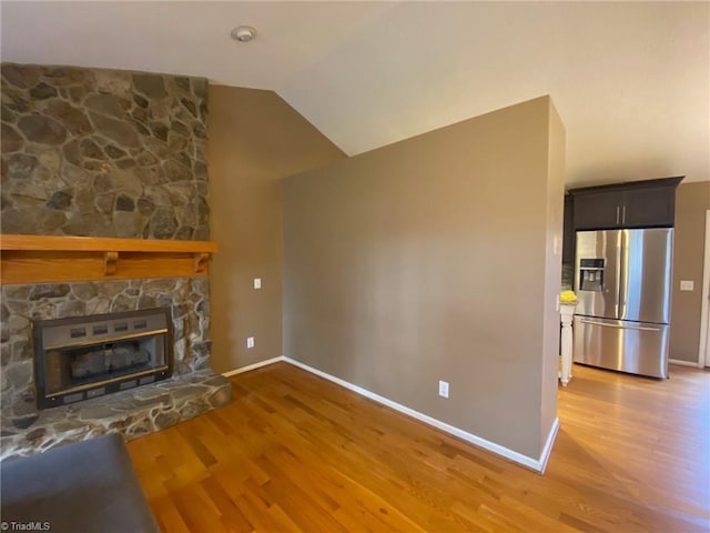 unfurnished living room featuring hardwood / wood-style flooring, a fireplace, and vaulted ceiling