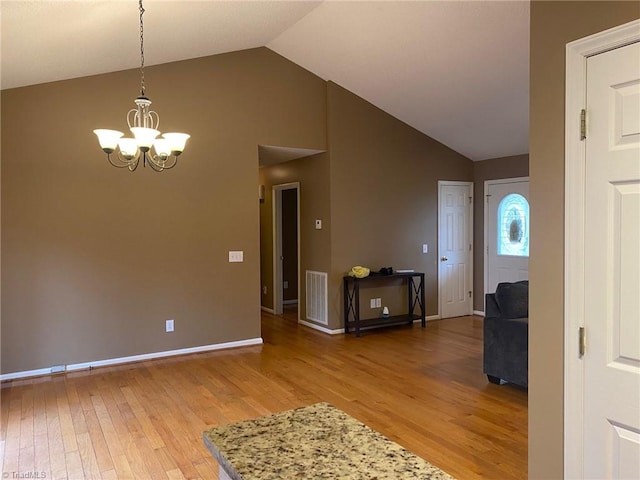 entryway featuring hardwood / wood-style flooring, high vaulted ceiling, and an inviting chandelier