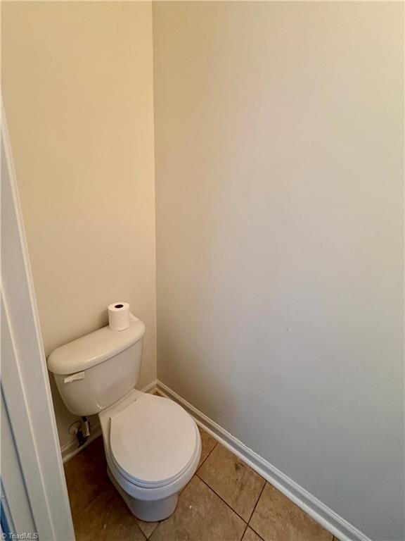 bathroom with baseboards, tile patterned floors, and toilet