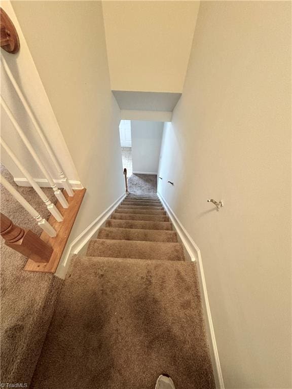 staircase featuring carpet flooring and baseboards