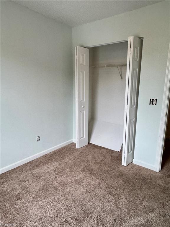 unfurnished bedroom featuring carpet floors, a closet, and baseboards