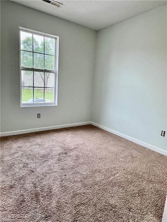 empty room featuring carpet, a textured ceiling, and baseboards