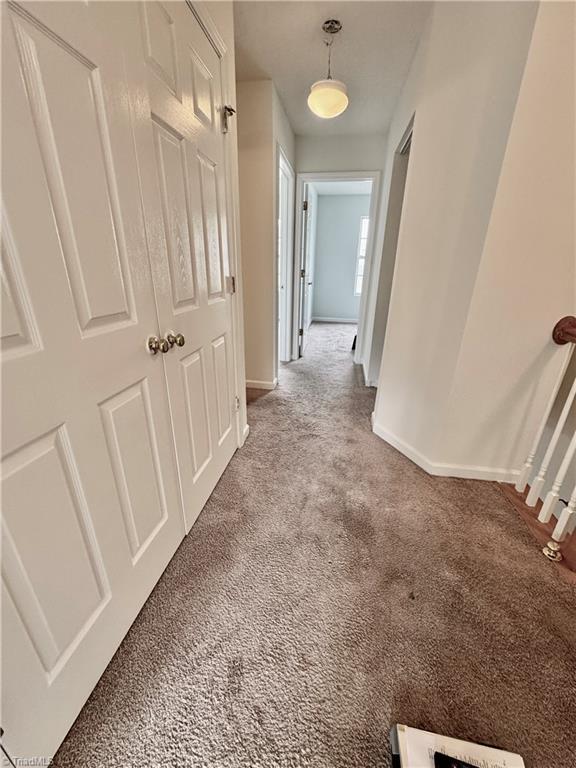 hallway featuring carpet flooring and baseboards