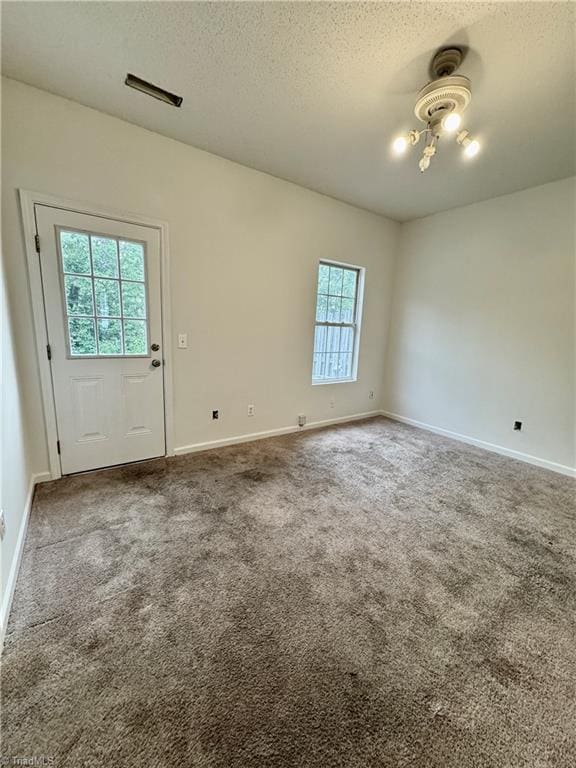 carpeted empty room with a textured ceiling and baseboards