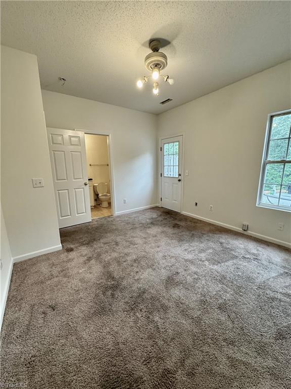 spare room featuring a textured ceiling, baseboards, and carpet flooring