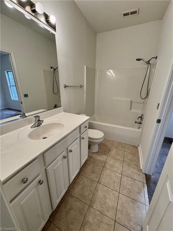 bathroom with tile patterned flooring, toilet, vanity, and shower / bath combination