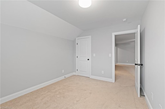 unfurnished bedroom with vaulted ceiling and light carpet