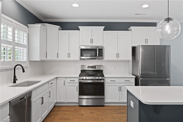 kitchen with pendant lighting, appliances with stainless steel finishes, sink, and white cabinets