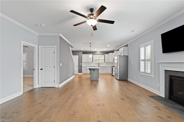 unfurnished living room featuring ornamental molding, light wood-type flooring, and a wealth of natural light