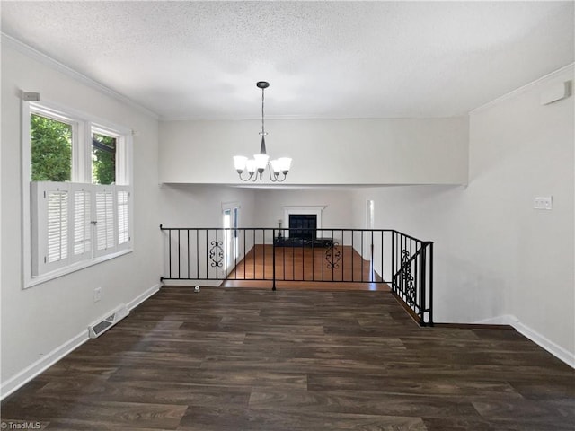 spare room featuring a notable chandelier, visible vents, ornamental molding, and wood finished floors