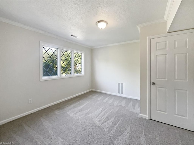 empty room featuring crown molding, carpet floors, baseboards, and visible vents