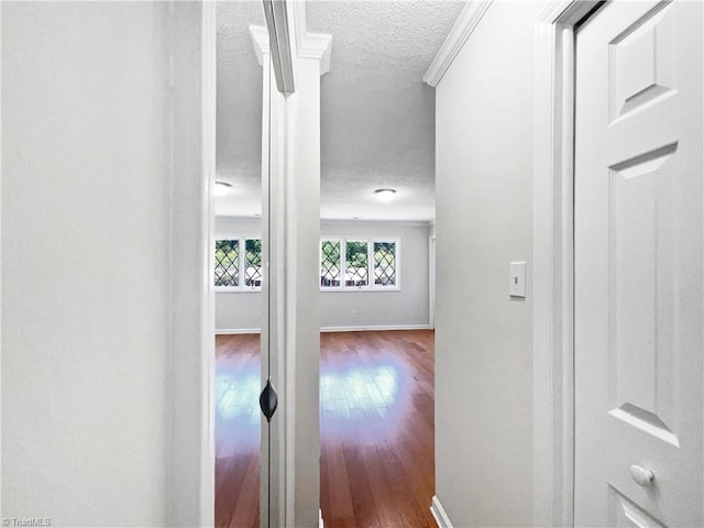 hallway featuring baseboards, a textured ceiling, and hardwood / wood-style floors