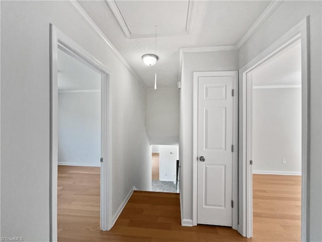 hallway with crown molding, baseboards, wood finished floors, and attic access
