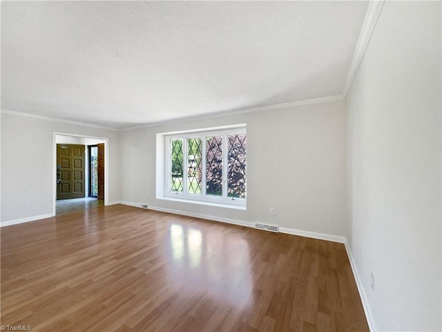 unfurnished living room featuring baseboards, ornamental molding, wood finished floors, and visible vents