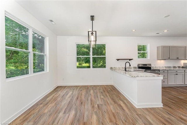 4000 Groometown Rd, Greensboro, NC 27407 - kitchen with stainless steel range with electric stovetop, wood finished floors, a peninsula, light stone counters, and recessed lighting