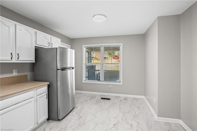 kitchen with visible vents, marble finish floor, freestanding refrigerator, and white cabinets