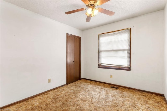 carpeted empty room with a ceiling fan, visible vents, baseboards, and a textured ceiling