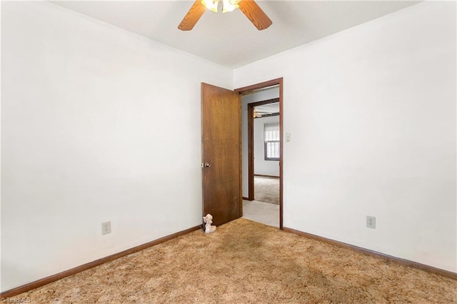 carpeted empty room featuring baseboards and ceiling fan