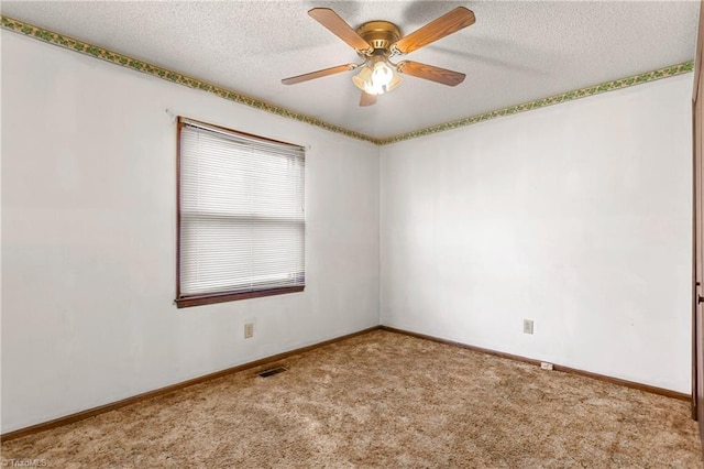 spare room featuring carpet, baseboards, and a textured ceiling