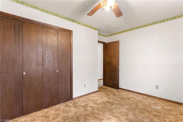 unfurnished bedroom featuring a closet, baseboards, carpet, and a ceiling fan