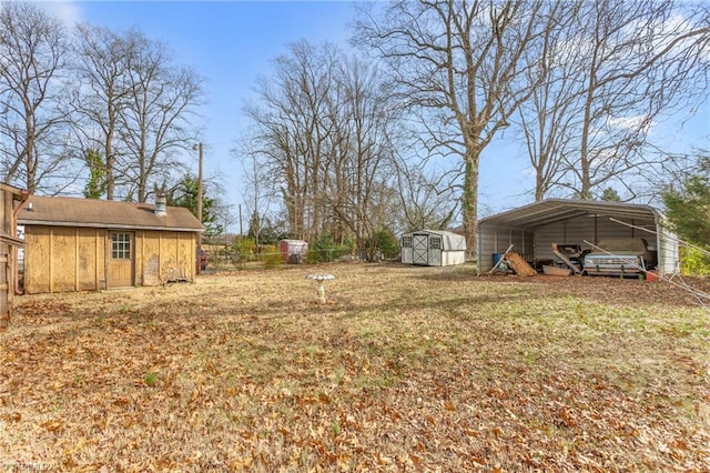 view of yard with fence, an outbuilding, a carport, and a shed