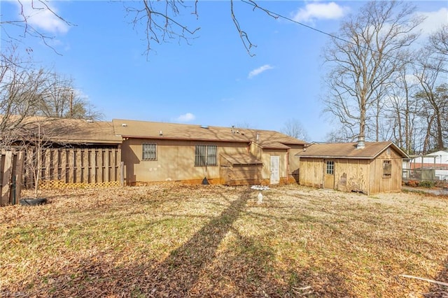 rear view of house featuring a lawn and fence