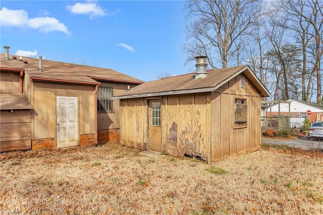 rear view of house with an outdoor structure and fence