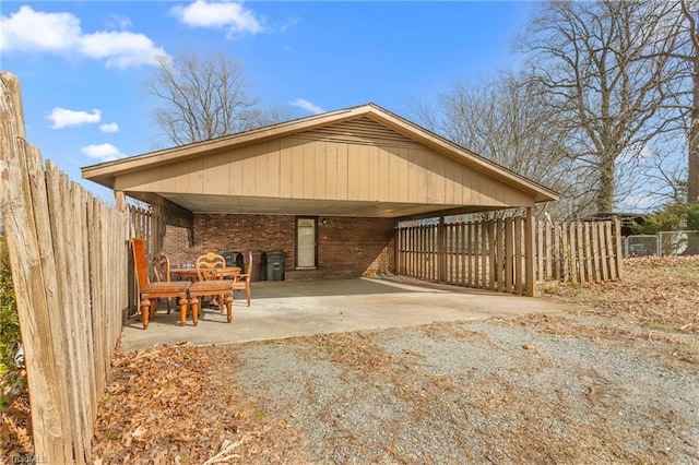 back of house with a carport, fence, brick siding, and driveway