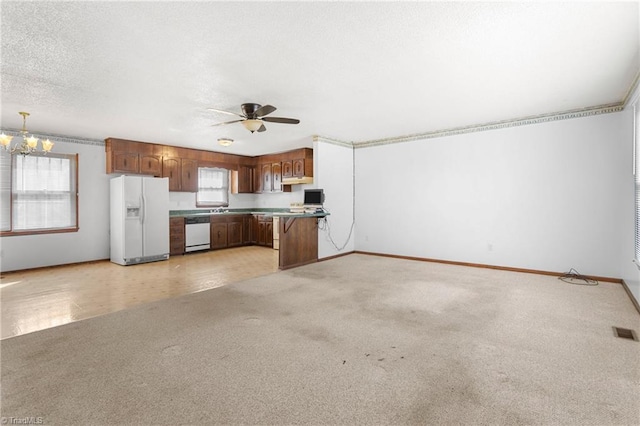 kitchen featuring visible vents, open floor plan, light colored carpet, white appliances, and a textured ceiling