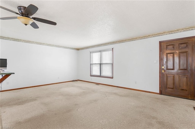 carpeted spare room featuring a textured ceiling, baseboards, and a ceiling fan