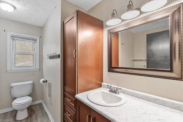 bathroom featuring vanity, hardwood / wood-style flooring, a textured ceiling, and toilet