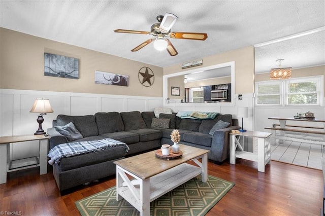 living room with dark hardwood / wood-style flooring, a textured ceiling, and ceiling fan