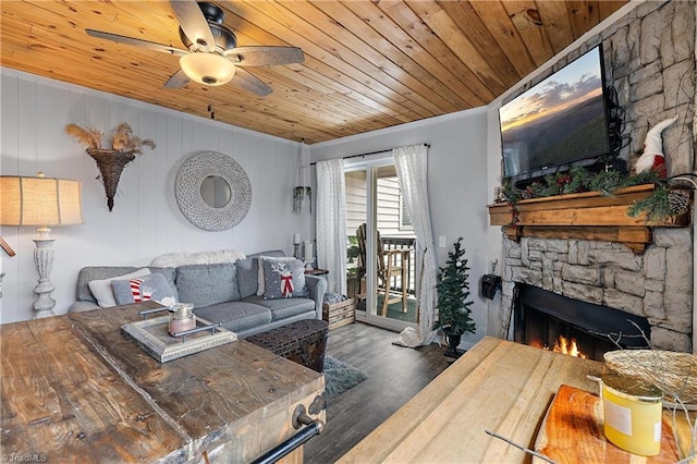 living room featuring wood ceiling, a stone fireplace, ornamental molding, ceiling fan, and dark hardwood / wood-style floors