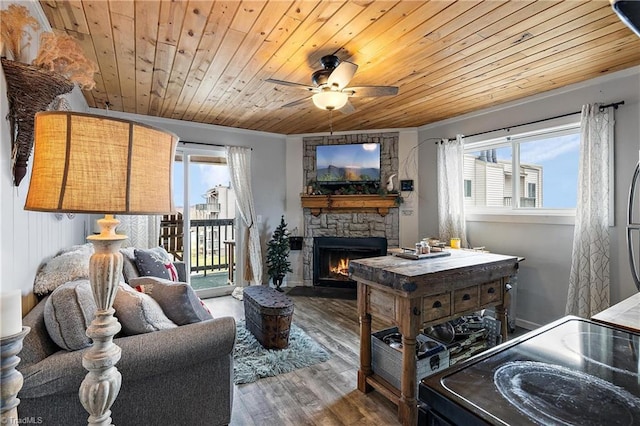 living room featuring hardwood / wood-style flooring, ceiling fan, wooden ceiling, and a stone fireplace