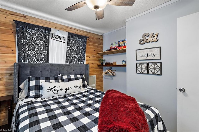 bedroom with wooden walls, a textured ceiling, ceiling fan, and crown molding