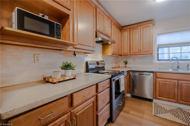 kitchen featuring sink, decorative backsplash, light hardwood / wood-style floors, light stone counters, and stainless steel appliances