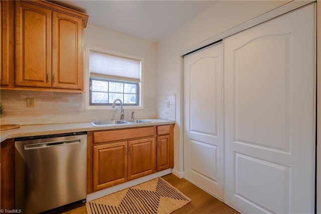 kitchen with dishwasher, sink, light hardwood / wood-style floors, and decorative backsplash