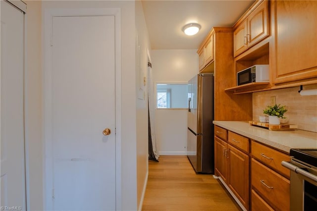 kitchen featuring tasteful backsplash, light wood-type flooring, and stainless steel refrigerator