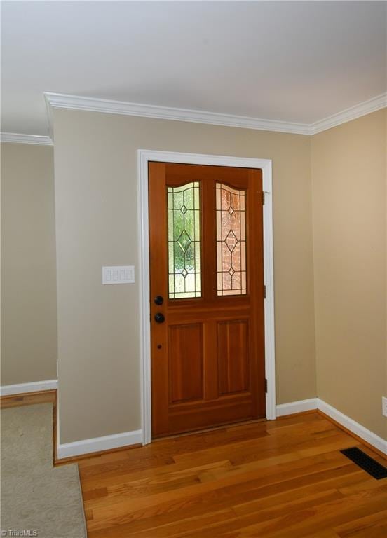 foyer entrance featuring crown molding and light hardwood / wood-style flooring