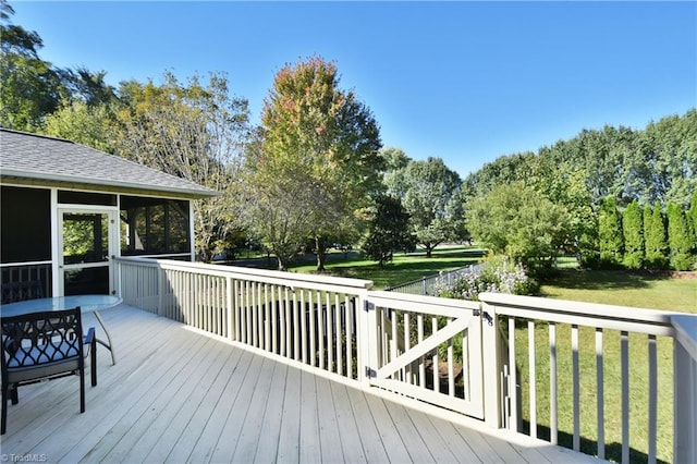 wooden terrace featuring a sunroom and a lawn