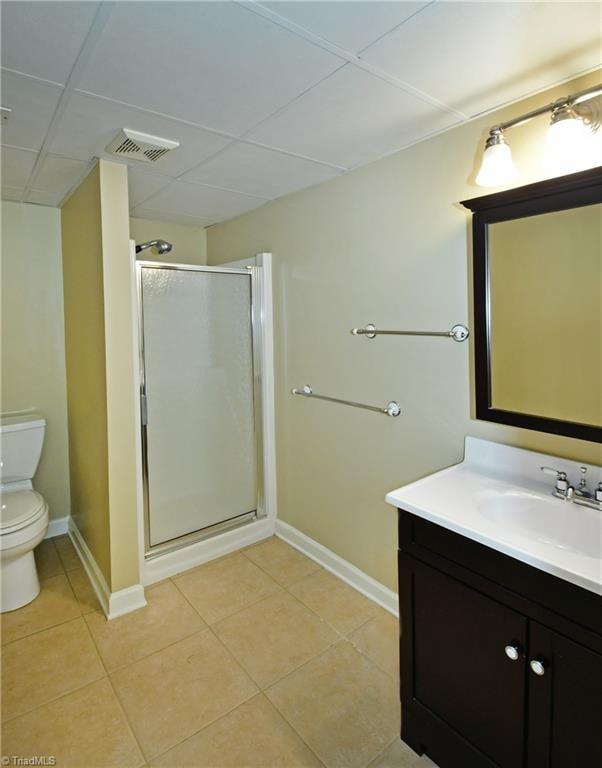 bathroom with vanity, toilet, a shower with door, and tile patterned floors