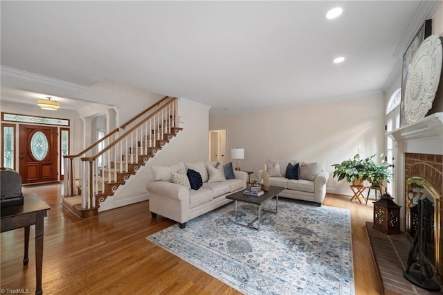 6303 Reata Ct, Summerfield, NC 27358 - living room featuring stairs, a brick fireplace, wood finished floors, recessed lighting, and ornamental molding