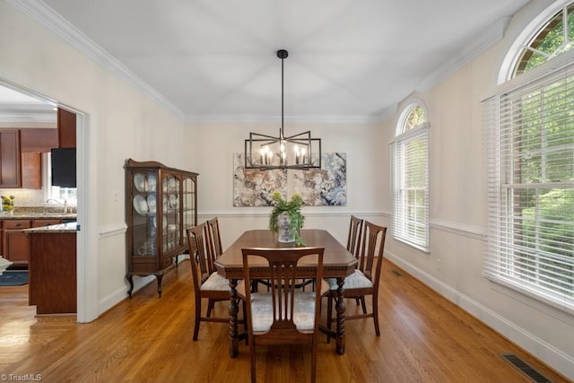 6303 Reata Ct, Summerfield, NC 27358 - dining room with a chandelier, light wood finished floors, and crown molding