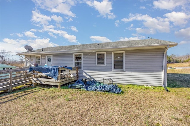 rear view of property featuring a deck and a lawn