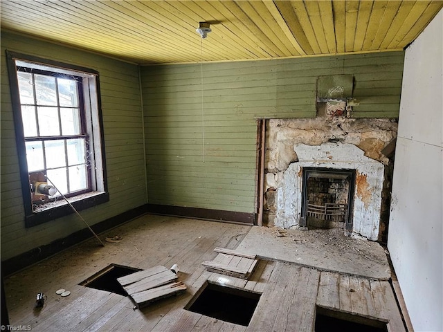 unfurnished living room with hardwood / wood-style flooring, wood walls, wood ceiling, and a fireplace