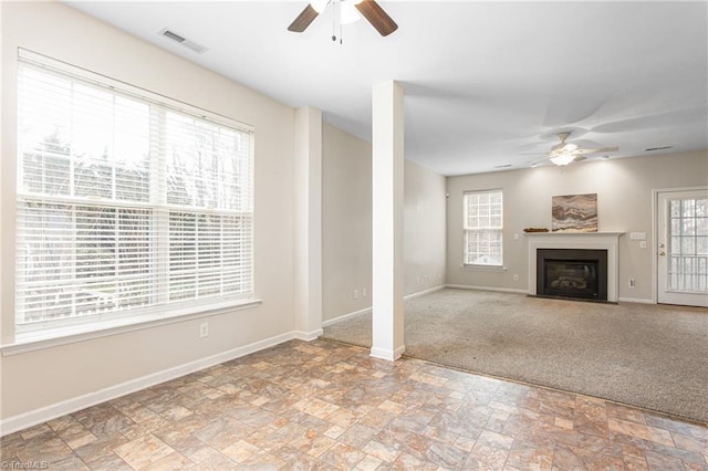 unfurnished living room with baseboards, visible vents, and ceiling fan